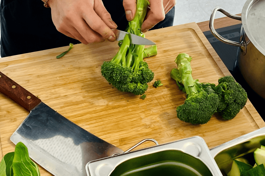 Mann schneidet Brokoli mit Messer